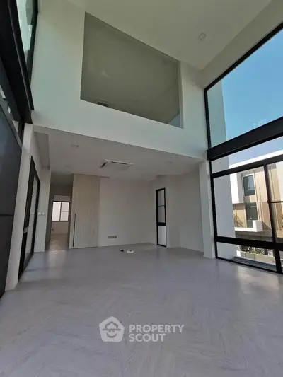 Spacious modern living room with high ceilings and large windows offering abundant natural light.