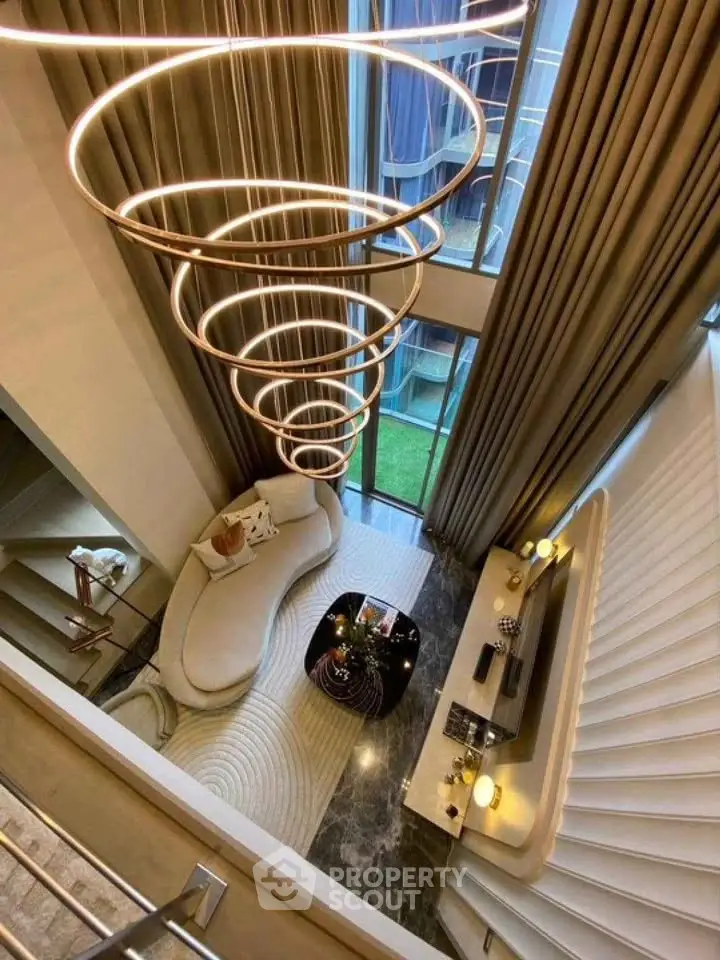 Luxurious modern living room with high ceilings, elegant lighting, and floor-to-ceiling windows.