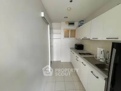 Modern kitchen with sleek white cabinets and compact appliances in a cozy apartment.