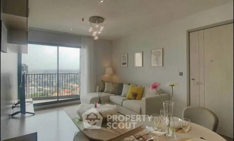 Modern living room with large window and stylish decor in high-rise apartment.