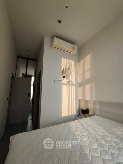 Modern bedroom with air conditioning and natural light, featuring a comfortable bed and minimalist decor.