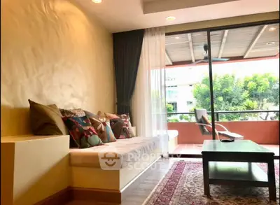 Spacious living room with cozy seating and large balcony overlooking lush greenery.