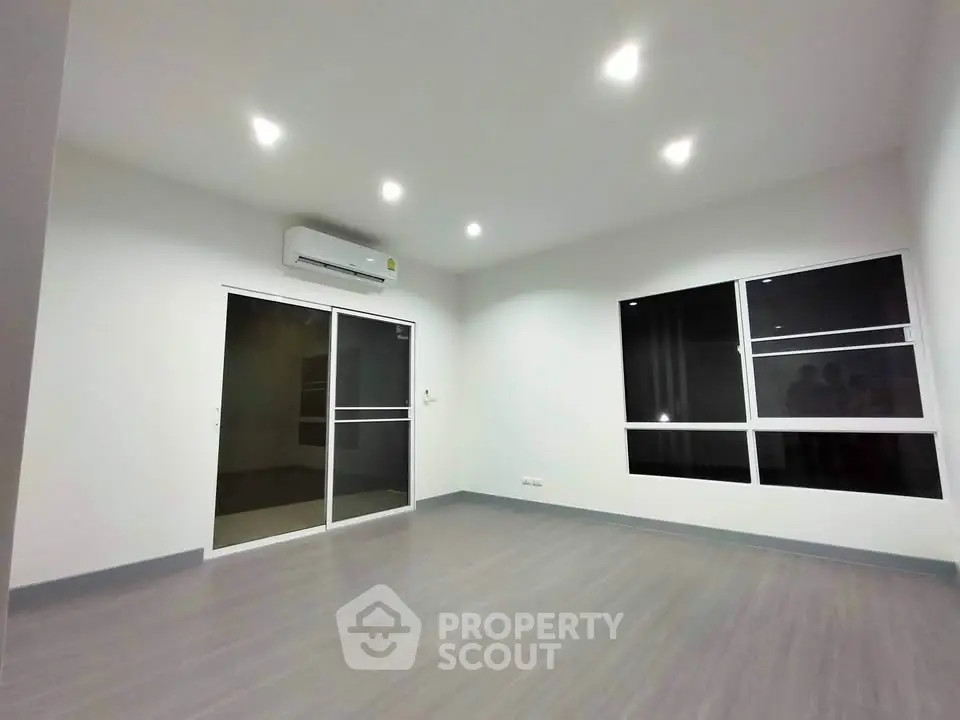 Spacious modern living room with sleek flooring and large windows, perfect for natural light.