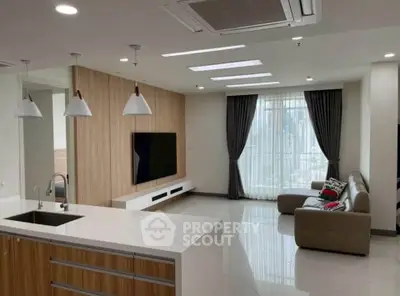 Modern living room with open kitchen, sleek design, and ample natural light.