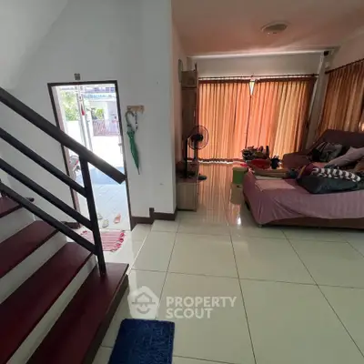 Spacious living room with modern staircase and cozy seating area, perfect for family gatherings.