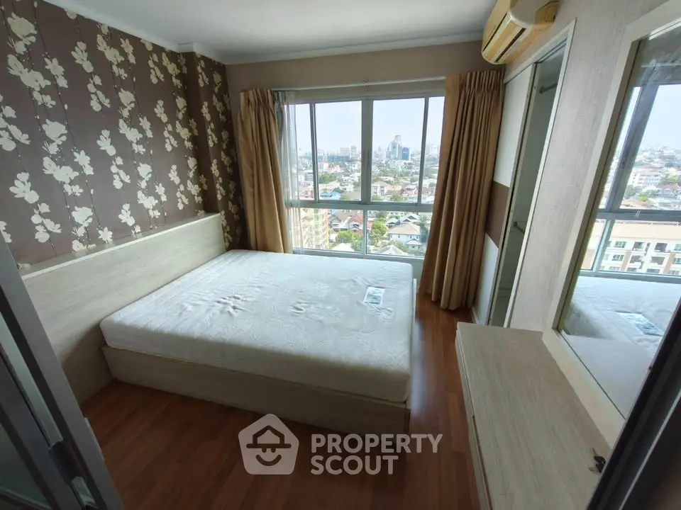 Spacious bedroom with large window offering stunning city views, featuring elegant wallpaper and wooden flooring.