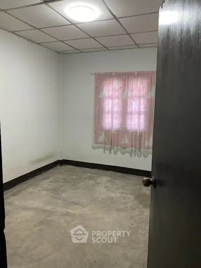 Spacious empty room with concrete floor and pink curtains, ideal for customization.