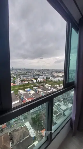 Stunning cityscape view from high-rise apartment window, showcasing urban skyline and cloudy sky.