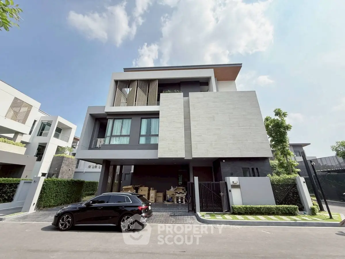 Modern three-story house with sleek design and spacious driveway in upscale neighborhood.