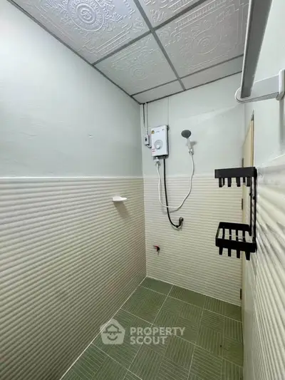 Compact bathroom with green tiles and modern shower setup