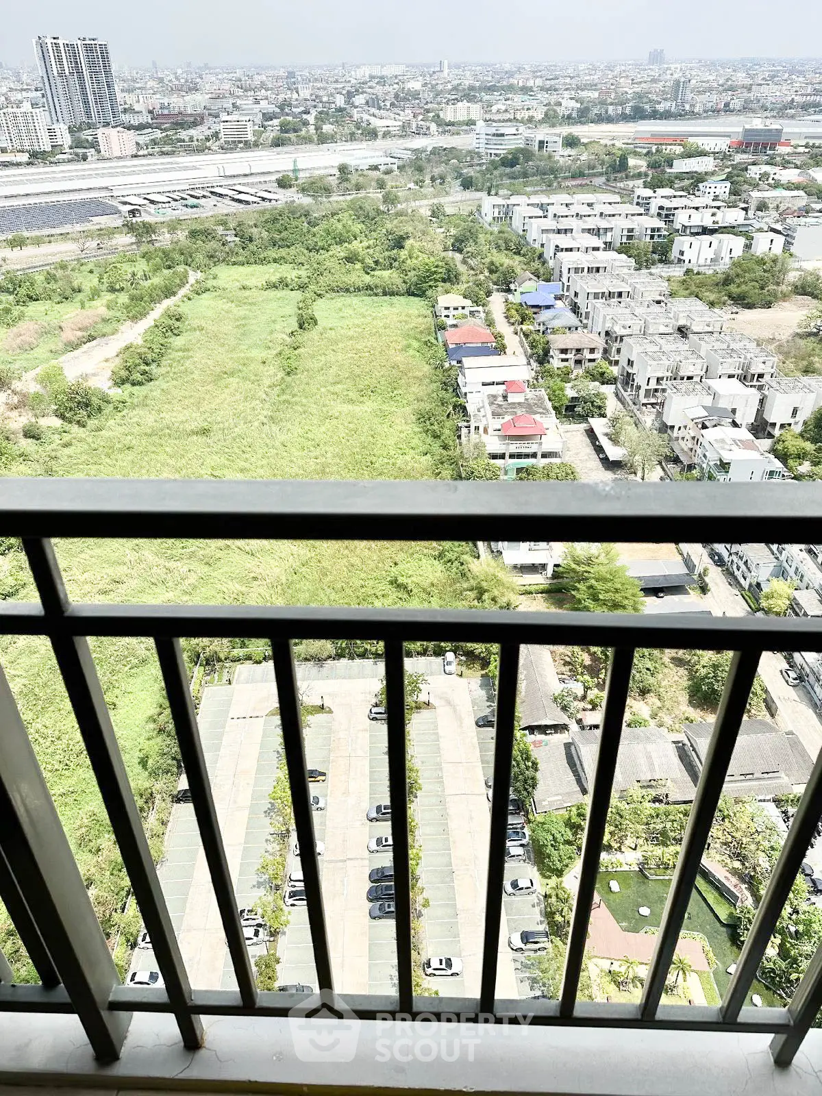 Stunning high-rise balcony view overlooking cityscape and greenery, perfect for urban living.