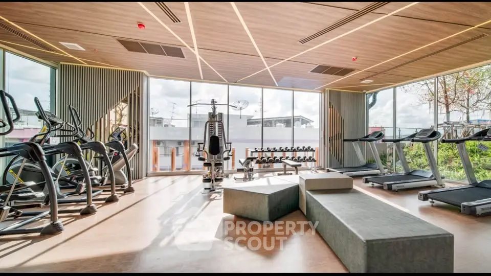 Modern gym with state-of-the-art equipment and panoramic windows in luxury residential building.