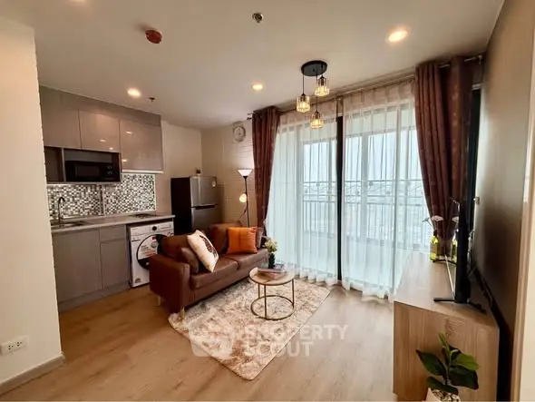 Modern open-layout living room with kitchen, cozy sofa, and large balcony windows.