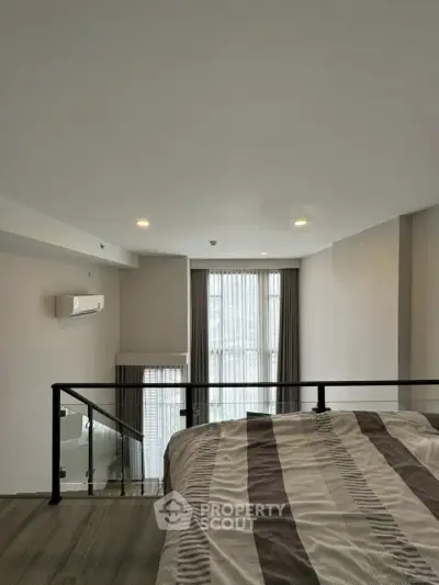 Modern bedroom with large window and stylish decor in a contemporary apartment.