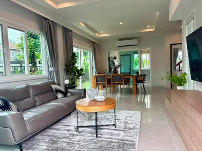 Spacious modern living room with elegant decor and dining area, featuring large windows and stylish furniture.