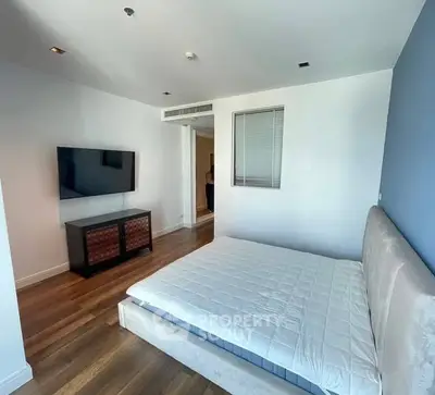 Modern bedroom with sleek wooden flooring and wall-mounted TV
