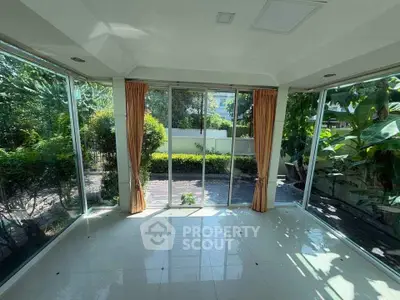 Spacious sunlit room with large windows overlooking lush garden, perfect for relaxation and nature views.