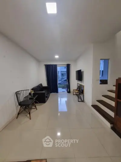 Spacious living room with modern decor and natural light, perfect for relaxation and entertainment.