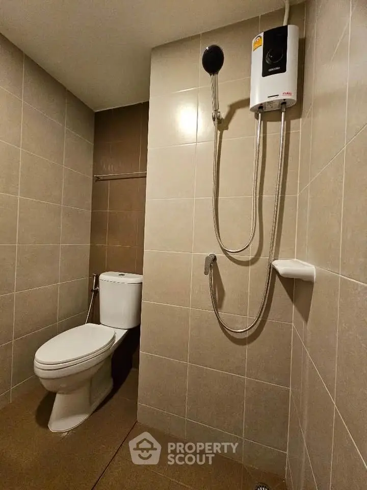 Modern bathroom with sleek tiles and shower heater in a contemporary apartment.