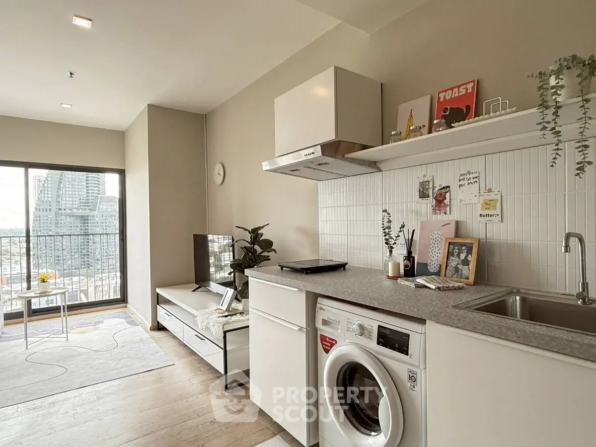 Modern open-plan living room and kitchen with city view, featuring sleek appliances and stylish decor.