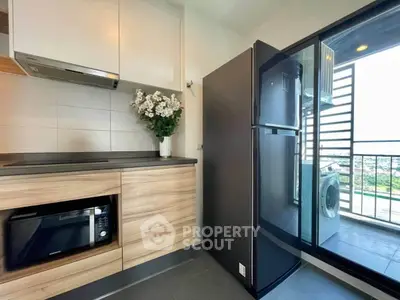 Modern kitchen with sleek appliances and balcony view, featuring a washing machine and stylish cabinetry.