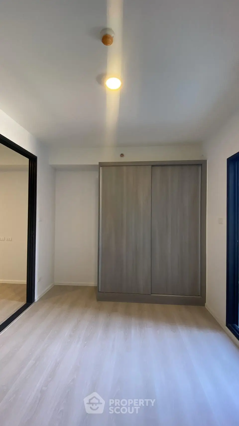 Spacious modern bedroom with sleek sliding wardrobe and elegant flooring.
