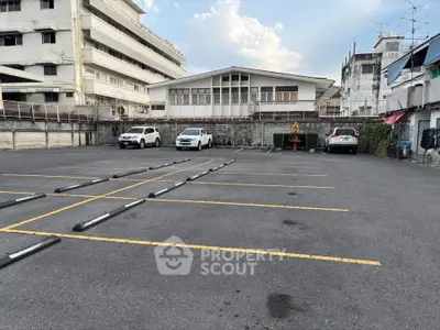 Spacious urban parking lot with multiple parking spaces and surrounding buildings.