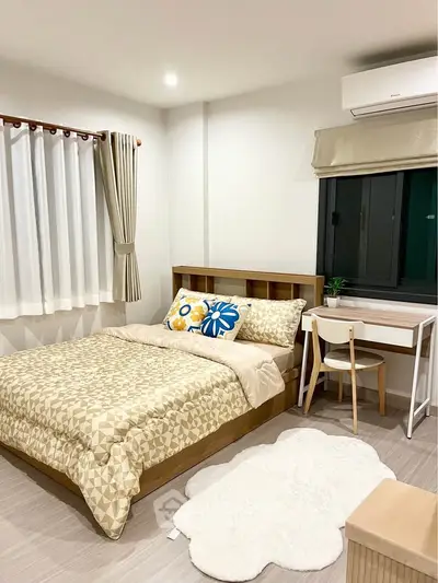 Cozy bedroom with modern decor and natural light, featuring a stylish bed and functional workspace.