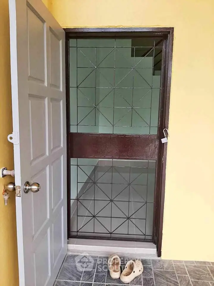 Inviting entrance with open door and tiled flooring, showcasing a welcoming home atmosphere.