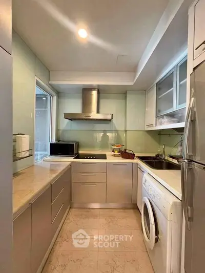 Modern kitchen with sleek cabinetry, built-in appliances, and washing machine in a compact layout.