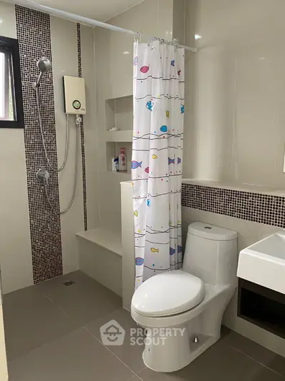 Modern bathroom with shower and toilet featuring fish-themed shower curtain