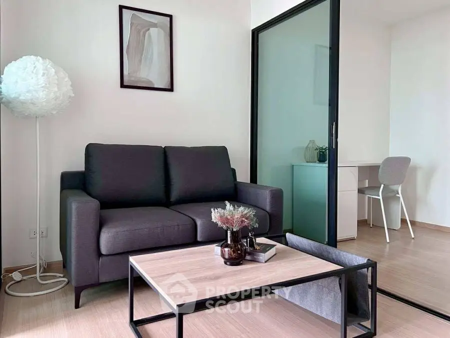 Modern living room with sleek sofa and stylish decor, adjacent to a cozy study area.