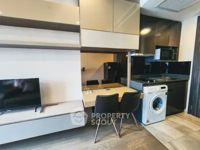 Modern kitchen with sleek cabinetry, washing machine, and dining area in a stylish apartment.