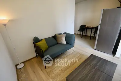 Modern living room with stylish sofa and dining area, featuring sleek wooden flooring and contemporary decor.