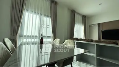 Modern dining area with elegant marble table and plush chairs, featuring large windows with sheer curtains.