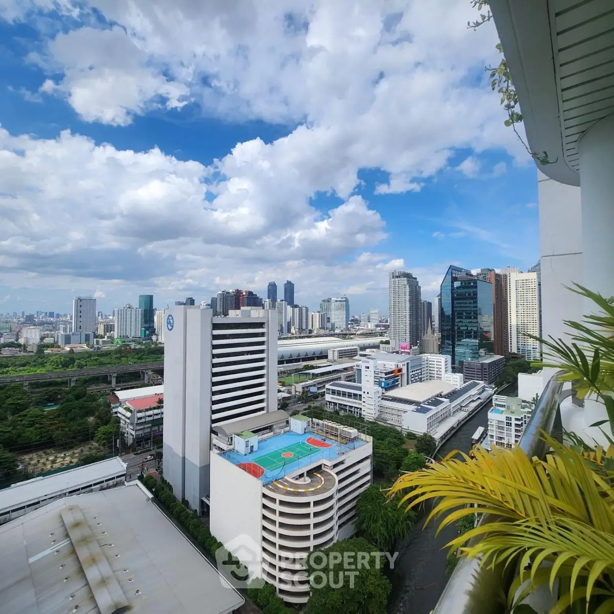 Stunning cityscape view from high-rise balcony with lush greenery and vibrant skyline.