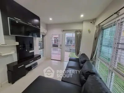 Modern living room with sleek black furniture and large windows for natural light.