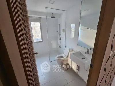 Modern bathroom with glass shower and sleek fixtures in bright apartment.