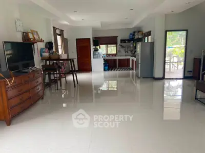 Spacious open-plan living room with modern kitchen and large windows.
