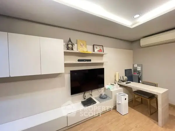 Modern living room with sleek furniture and wall-mounted TV, featuring minimalist design and air conditioning.