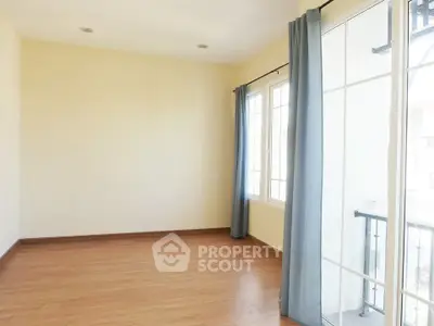 Spacious empty room with large windows and wooden flooring, perfect for customization.