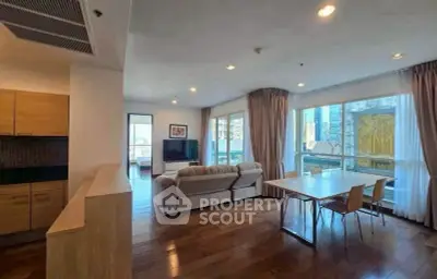 Spacious modern living room with large windows and wooden flooring in urban apartment.