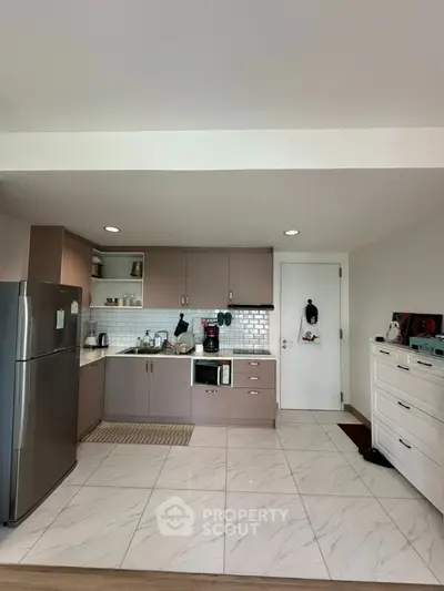 Modern kitchen with sleek cabinets and stainless steel fridge in open layout design.