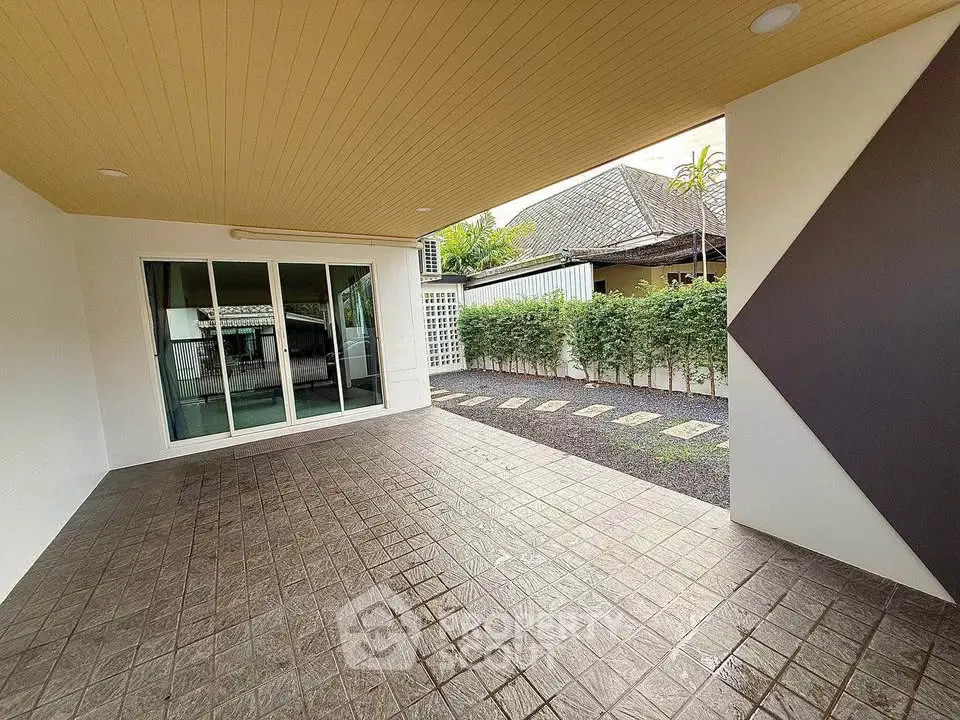 Spacious covered patio with modern design and garden view, perfect for outdoor relaxation.