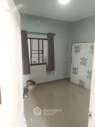 Spacious bedroom with tiled floor and large window, ideal for customization.