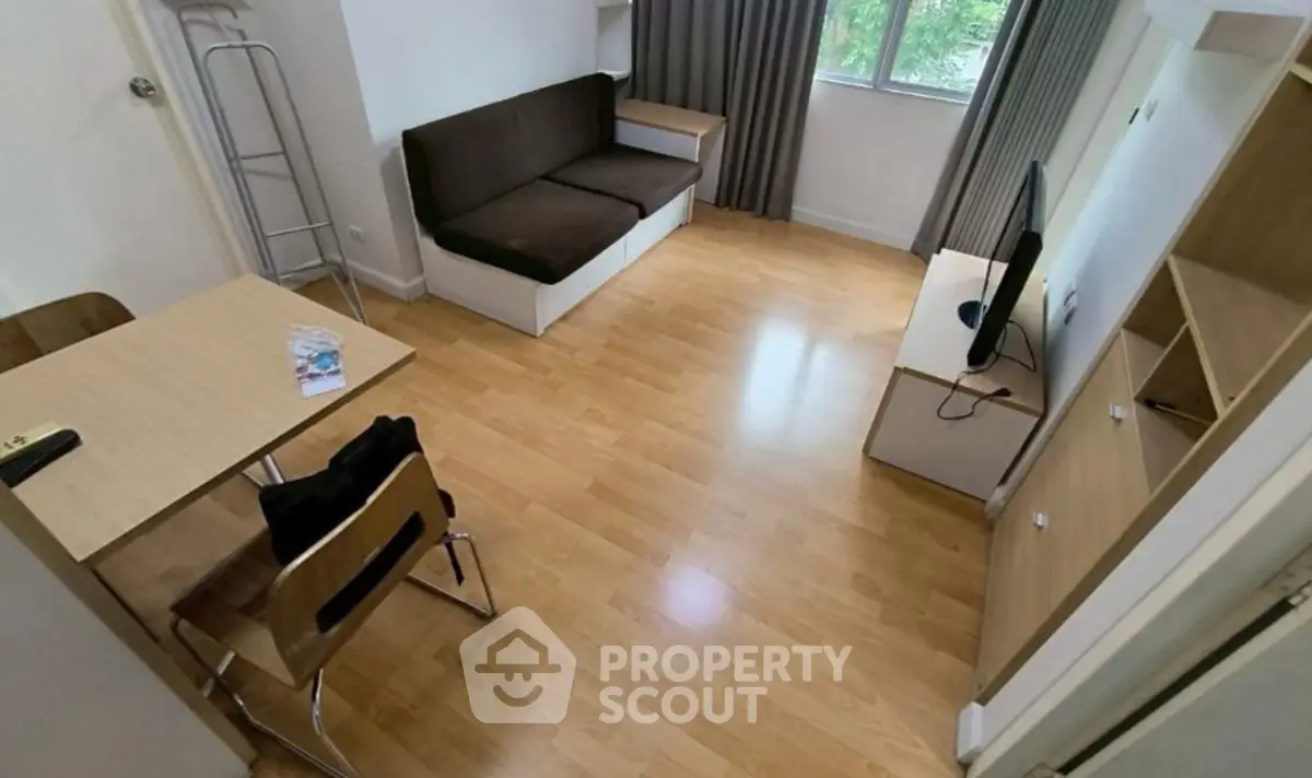 Cozy living room with wooden flooring, modern furniture, and natural light from window.