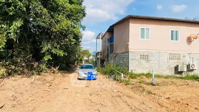 Spacious plot with adjacent house and car, ideal for development.