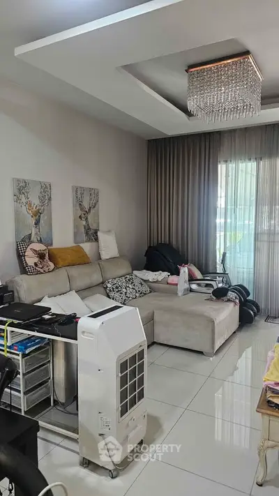 Modern living room with elegant chandelier and cozy sectional sofa, perfect for relaxation and entertainment.