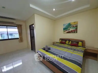 Spacious bedroom with modern decor and large window for natural light.