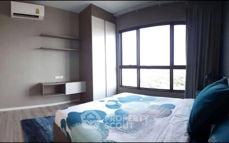 Modern bedroom with large window and stylish decor, offering a bright and inviting atmosphere.